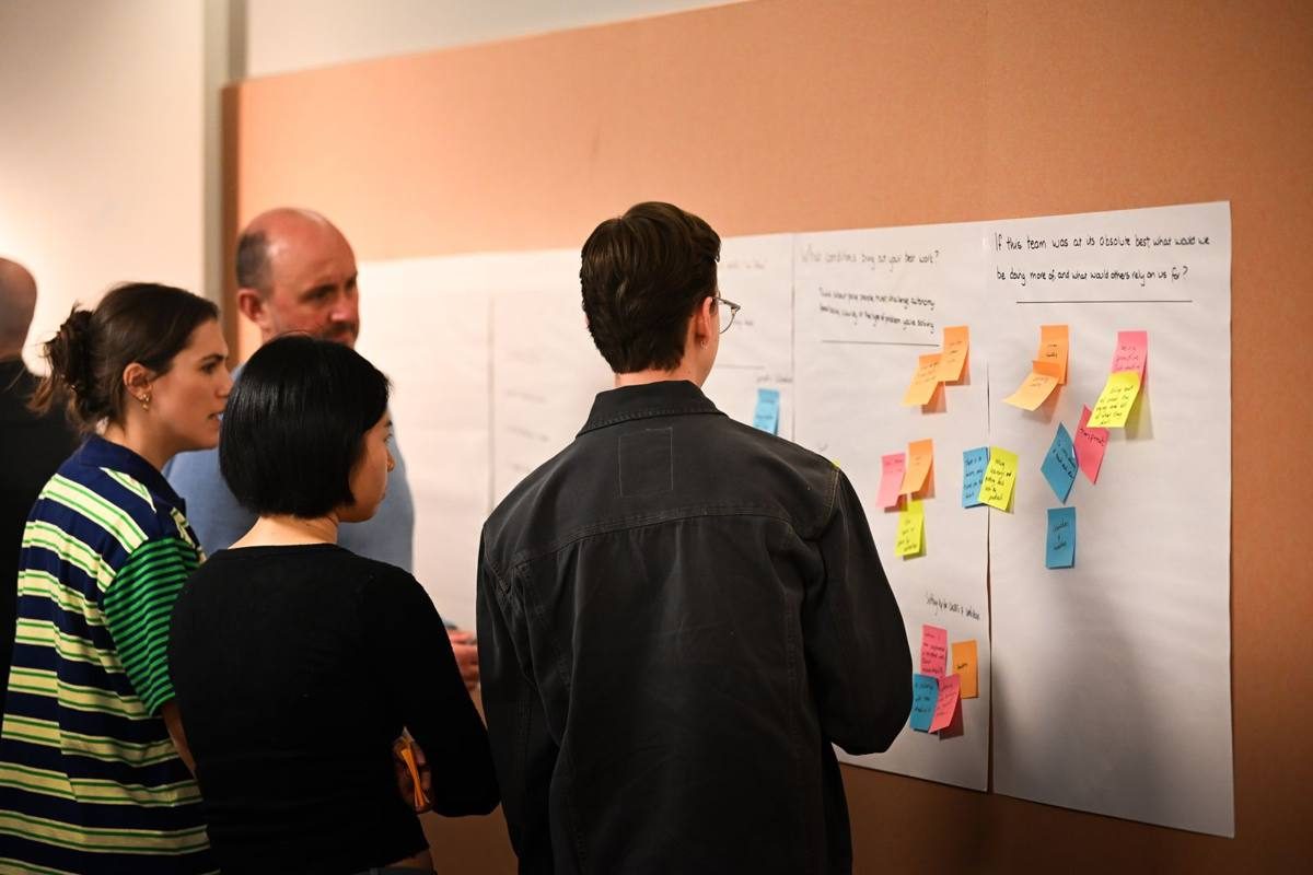 A workshop team mapping a process on a wall of notes